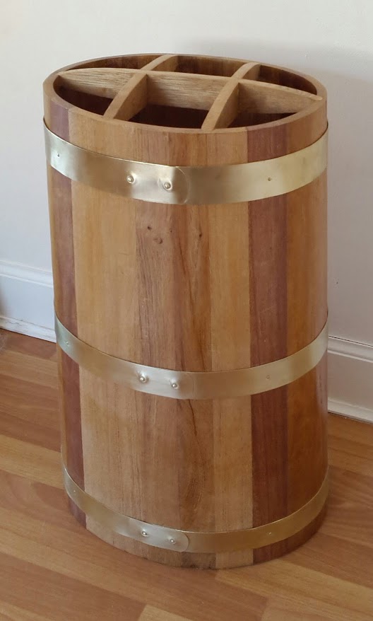 Wooden oak coopered umbrella stand with brass hoops sitting on wooden floor.