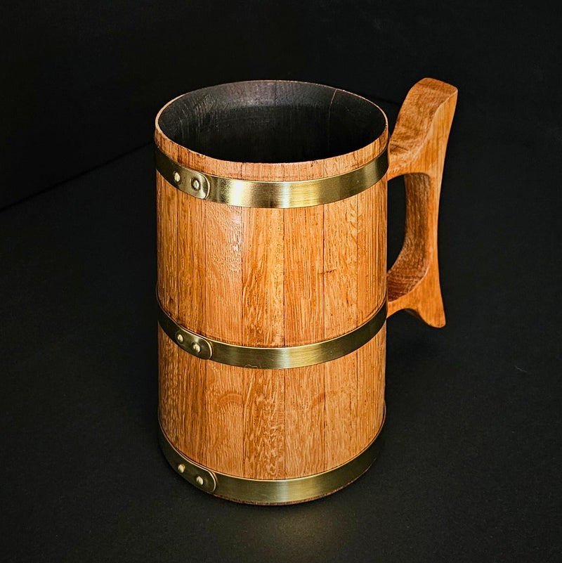 Handmade wooden oak 1L Tankard with wooden handle and brass hoops on black backdrop.